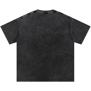 May include: A charcoal-coloured, short-sleeved t-shirt with a vintage, acid-wash effect. The shirt has a crew neck and a relaxed fit, ideal for casual wear. The fabric appears soft and slightly faded, giving it a worn-in look.