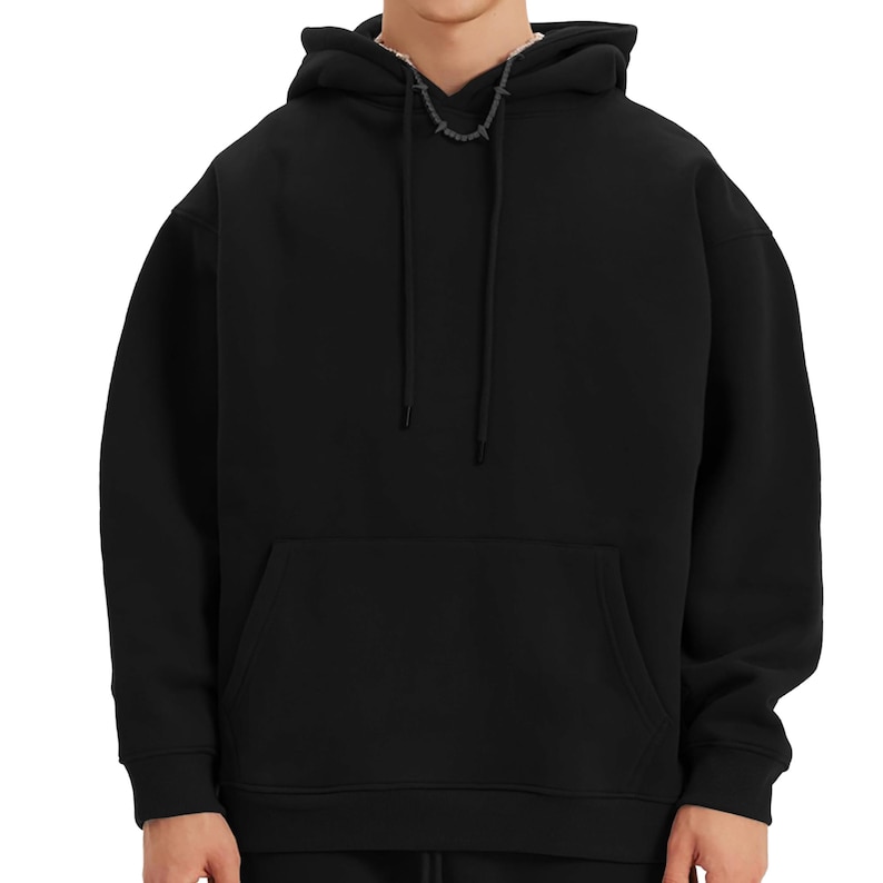 May include: A black hoodie with a kangaroo pocket and a drawstring hood. The sweatshirt has a relaxed fit and a minimalist design. A silver-coloured chain is visible at the neckline.