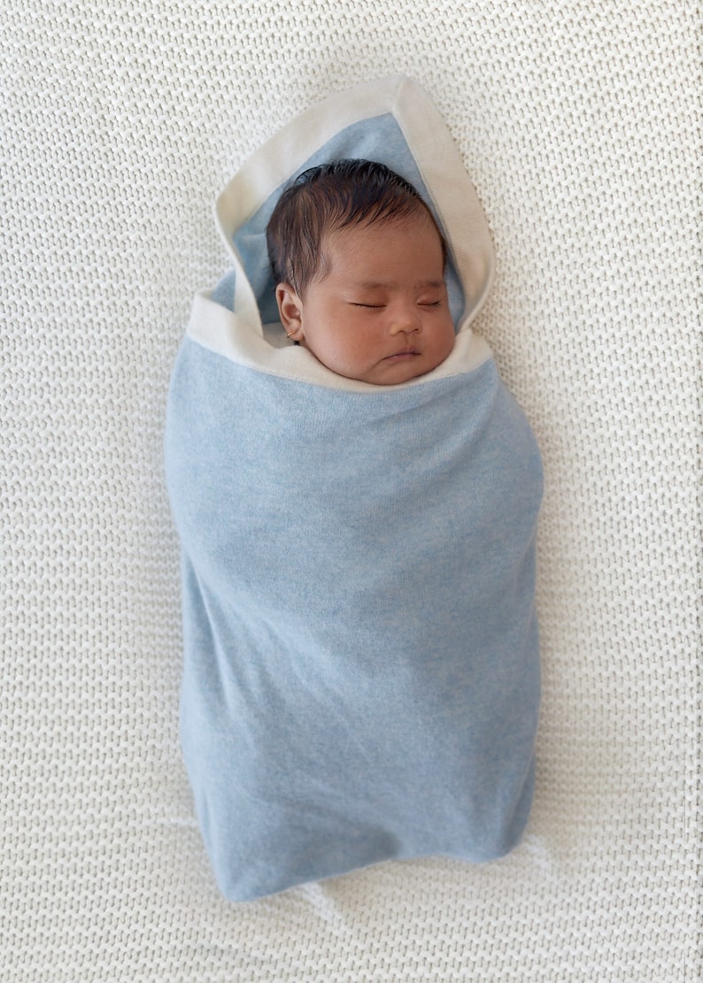 Un bébé emmailloté dans notre couverture en cachemire Botiboty. la couverture mesure 80x100cm et permet de tenir au chaud à la maison, en extérieur. le cachemire est une matière idéale pour la peau de bébé. Idéal pour un joli cadeau de naissance