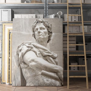 May include: A black and white photograph of a marble sculpture of a Roman emperor wearing a laurel wreath. The sculpture is displayed against a light gray background.