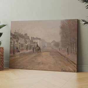 May include: A canvas print of a street scene in muted tones, reminiscent of Impressionist art. The artwork depicts a wide road with buildings, trees, and figures, including a horse-drawn carriage. The artist's signature, "Claude Monet," is visible in the lower right corner.