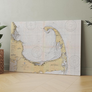May include: A vintage nautical chart of Cape Cod Bay, featuring detailed lines and markings. The chart is printed on a cream-colored background with yellow and brown accents. The text "CAPE COD BAY" is visible in the lower center of the chart.