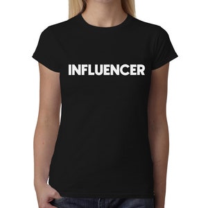 Può includere: Maglietta nera con la parola "INFLUENCER" stampata in bianco sul davanti.