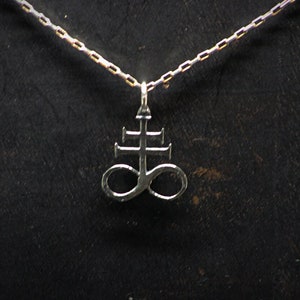 May include: A silver necklace with a pendant featuring a stylised symbol of a cross with an infinity symbol at the bottom.