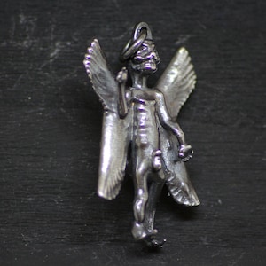 May include: A silver pendant featuring a skeletal angel with outstretched wings. The angel is depicted with a halo and a skeletal face.