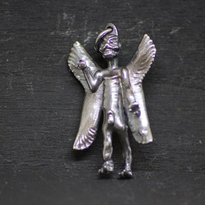 May include: A silver angel pendant with wings and a detailed face. The angel is standing with its arms outstretched.