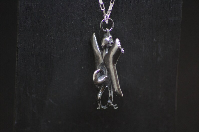 May include: Silver pendant necklace featuring a detailed sculpture of a mythical bird, a symbol of Liverpool, England.