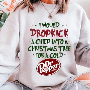 May include: A light gray sweatshirt with the text "I WOULD DROPKICK A CHILD INTO A CHRISTMAS TREE FOR A COLD" in red and green. The Dr. Pepper logo is at the bottom.