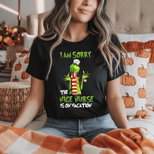May include: Black t-shirt with a green cartoon character in a nurse's uniform, including a white hat and a red and white striped scarf. The text on the shirt says "I AM SORRY THE NICE NURSE IS ON VACATION."