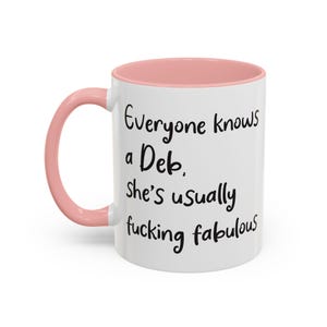 Peut inclure: Mug en céramique blanche avec intérieur et anse roses. Le mug porte l'inscription "Everyone knows a Deb, she's usually fucking fabulous" en écriture noire. Idée cadeau humoristique.