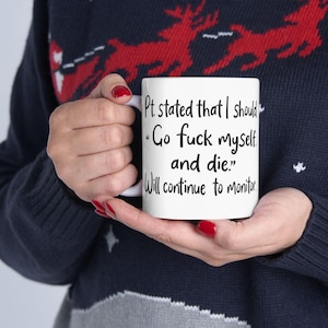 May include: White ceramic mug with black text that reads "Pt. stated that I should 'Go fuck myself and die.' Will continue to monitor." The mug is held by a person wearing a dark blue sweater with a red and white pattern.