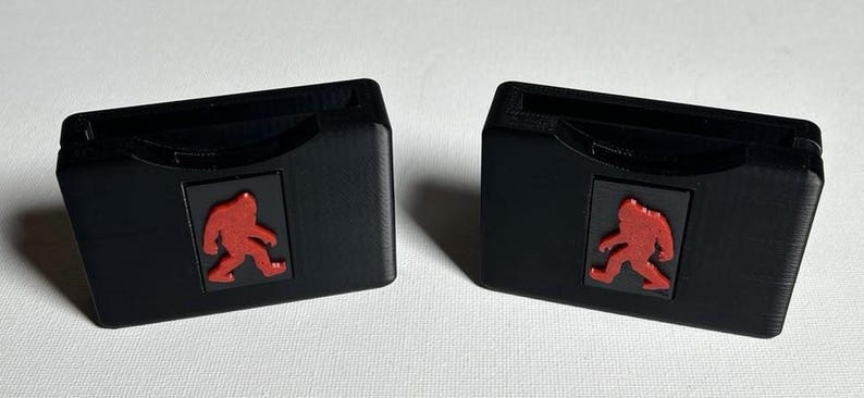 May include: Two black plastic cases with a red silhouette of a Bigfoot on the front. Each case has a slot for a game cartridge.