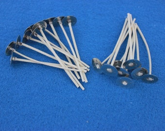 May include: A close-up of two piles of white candle wicks with metal bases. The wicks are arranged in a neat pile on a blue surface.