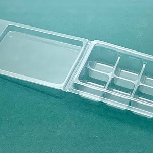 Può includere: Un imballaggio in plastica trasparente a conchiglia con un coperchio incernierato. Il coperchio ha una maniglia. Il fondo della conchiglia ha sei scomparti individuali.