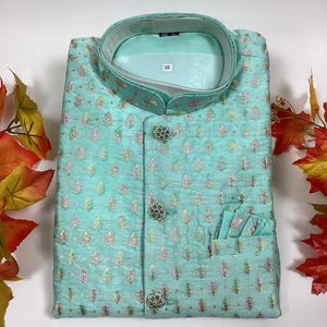 Pode incluir: Uma camisa azul claro estampada com colarinho mandarim e tr&ecirc;s bot&otilde;es. A camisa tem um bolso do lado direito e uma etiqueta de tamanho que diz "38".