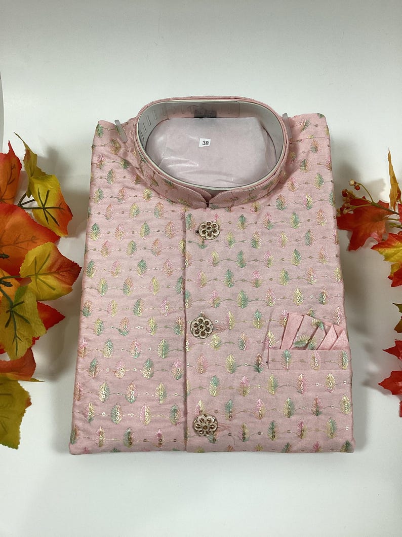 Pode incluir: Uma camisa rosa de bot&otilde;es com um padr&atilde;o floral e um pequeno bolso no lado esquerdo. A camisa tem uma gola mandarim e uma etiqueta de tamanho que diz "38".