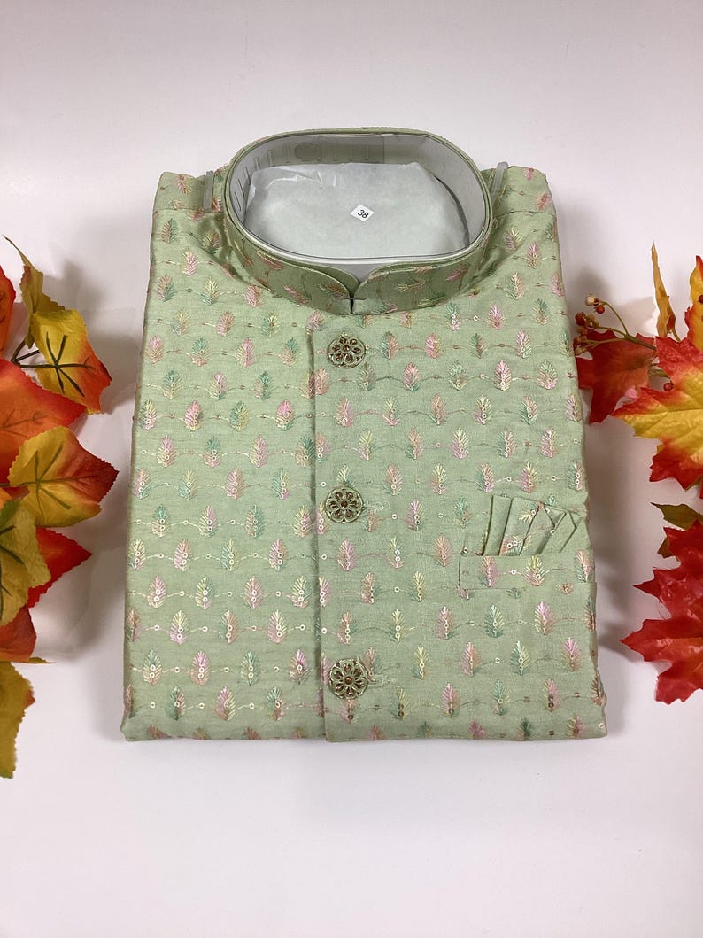 Pode incluir: Uma camisa verde estampada para homem com colarinho mandarim e fecho de bot&otilde;es. A camisa tem um bolso do lado direito e &eacute; decorada com bot&otilde;es dourados.