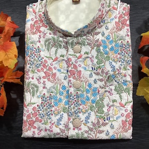 May include: White button-up shirt with a floral print featuring trees, flowers, and birds. The shirt has a mandarin collar and a button closure. The label on the shirt reads "38".
