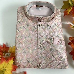 May include: A light pink embroidered waistcoat with a mandarin collar. The waistcoat features a geometric pattern with floral accents and decorative buttons. A small pocket is visible on the front. The size tag reads "38".
