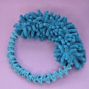 May include: A blue microfiber cleaning tool with a coiled handle. The tool is shaped like a ring and has a fluffy texture.