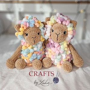 Puede incluir: Dos ovejas de ganchillo hechas a mano. Las ovejas son marrones con melenas y acentos de hilo colorido. Los juguetes tienen ojos de botón y están sentados sobre una superficie blanca. El texto "CRAFTS by Lindae" está en la parte inferior.