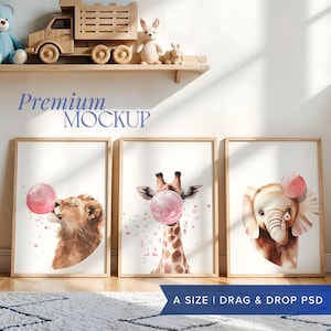 May include: Three framed watercolor illustrations of animals blowing pink bubble gum. The illustrations feature a lion, a giraffe, and an elephant. The frames are light brown wood and are hanging on a white wall.
