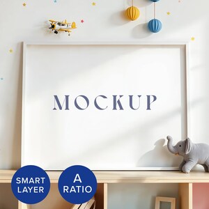 May include: A white picture frame with the word "MOCKUP" in blue text on a white background. The frame is on a wooden shelf with a small grey elephant toy and two circles that say "SMART LAYER" and "A RATIO".