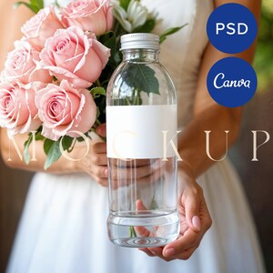 Puede incluir: Una botella de vidrio transparente con una etiqueta blanca y una tapa plateada. La botella está llena de agua y tiene un ramo de rosas rosas delante.