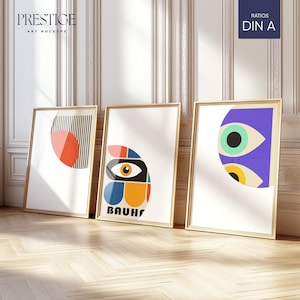 May include: Three framed art prints with abstract geometric designs. The prints are in gold frames and are hanging on a white wall. The prints feature a red and white circle, a colorful eye, and a blue and yellow eye.