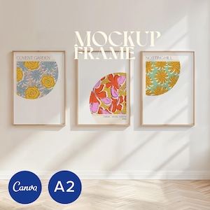 May include: Three framed art prints with floral designs. The prints feature a half-circle of flowers in yellow, pink, and orange against white backgrounds. The top of the frames have the text "MOCKUP FRAME". The bottom has the text "Canva" and "A2".