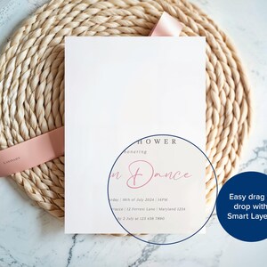 May include: A white invitation card with the text "Shower Honoring + Dance" in pink script, tied with a pink ribbon, rests on a woven placemat. The card includes event details. The background is a marble surface.
