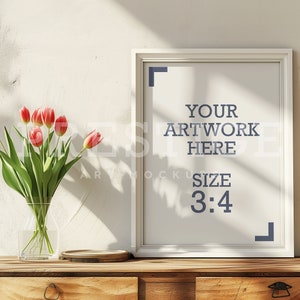 Könnte beinhalten: Ein weißer Bilderrahmen mit einem weißen Passepartout auf einem Holztisch. Der Rahmen ist leer und trägt den Text "YOUR ARTWORK HERE SIZE 3:4". Ein Strauß rosa Tulpen in einer durchsichtigen Glasvase steht auf dem Tisch links neben dem Rahmen.