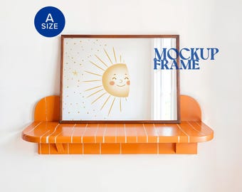 Può includere: Una stampa incorniciata con un'illustrazione di un sole sorridente e stelle. L'opera d'arte è esposta su una mensola arancione con un motivo a piastrelle bianche. Le parole "MOCKUP FRAME" sono stampate in blu.