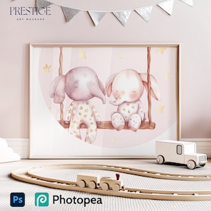 Könnte beinhalten: Eine Aquarell-Illustration von zwei rosa Elefanten auf einer Schaukel mit goldenen Sternen im Hintergrund. Die Elefanten tragen florale Outfits und lächeln. Die Illustration ist in einem weißen Rahmen gerahmt und hängt an einer rosa Wand.