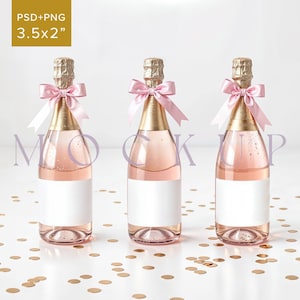 Op de afbeelding: Drie champagneflessen met roze strikken en witte etiketten op een wit oppervlak met gouden confetti. De flessen zijn 3,5 x 2 inch.