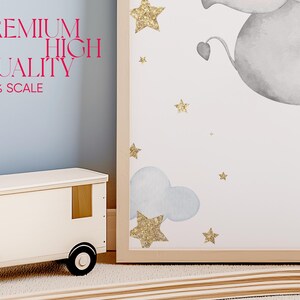 May include: A framed print with a watercolor illustration of a gray elephant flying in the sky with gold glitter stars and clouds. The print has the text "PREMIUM HIGH QUALITY 150% SCALE" on the bottom left corner.