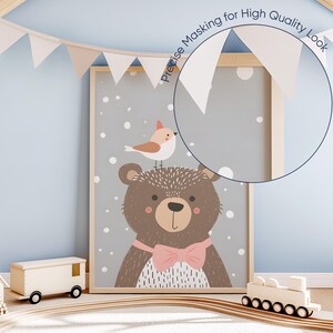 May include: A framed print with a cute cartoon illustration of a brown bear wearing a pink bow tie and a small bird perched on its head. The background is a light gray with white dots.