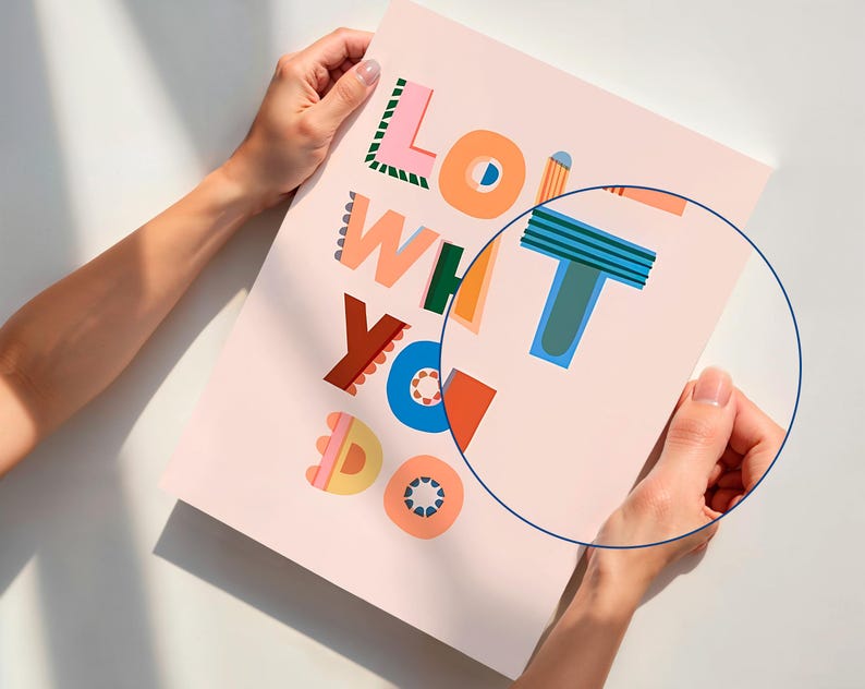 May include: A pink poster with the words "LOVE WHAT YOU DO" in colorful, playful typography. The letters are in various colors, including orange, blue, green, and pink. The poster is held by two hands.