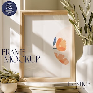 Puede incluir: Una maqueta de marco de madera con un paspartú blanco y una impresión floral abstracta colorida en el interior. El marco está sentado sobre una superficie blanca con un jarrón de ramas verdes y un cuenco de aceitunas verdes.