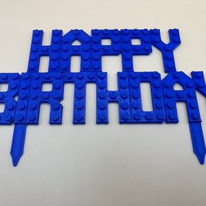 Blue 3D printed LEGO-style "Happy Birthday" cake topper for kids' birthday parties.
