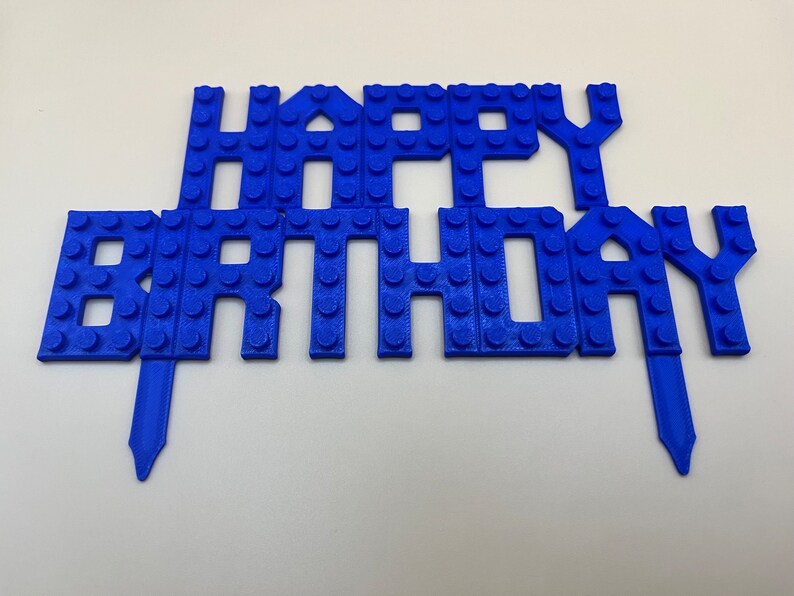 Blue 3D printed LEGO-style "Happy Birthday" cake topper for kids' birthday parties.