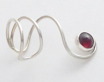 May include: A silver-colored metal ring featuring a spiral design that wraps around the finger. The band extends into a curved arm that terminates in a single, round, deep red gemstone set in a smooth, polished silver-colored metal bezel.