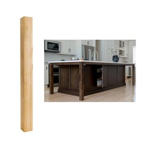 May include: A close-up of a light brown wooden kitchen island leg. The leg is square and has a smooth finish.