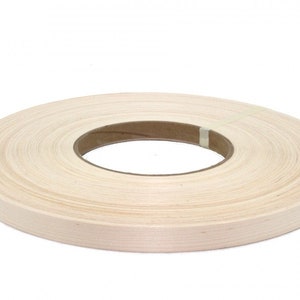 May include: A roll of natural wood veneer tape, perfect for edging furniture or crafts. The tape is wound around a brown cardboard core.