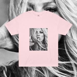 May include: A pink t-shirt with a black and white image of a woman with long hair smoking a cigarette.