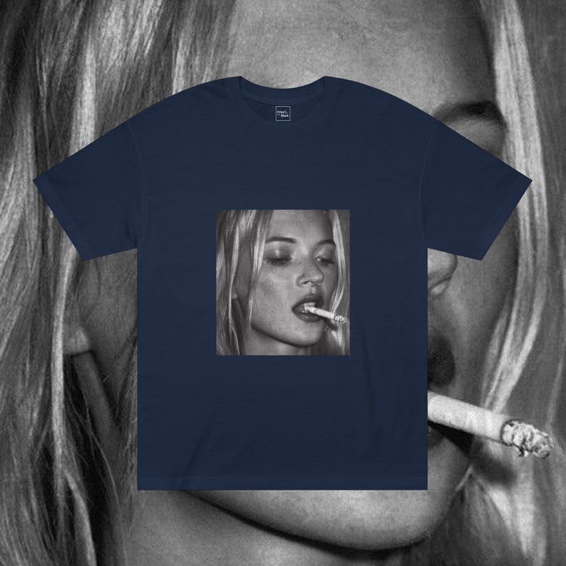 Puede incluir: Una camiseta azul marino con una foto en blanco y negro de una mujer fumando un cigarrillo. La mujer tiene el pelo rubio y lleva una camisa blanca.