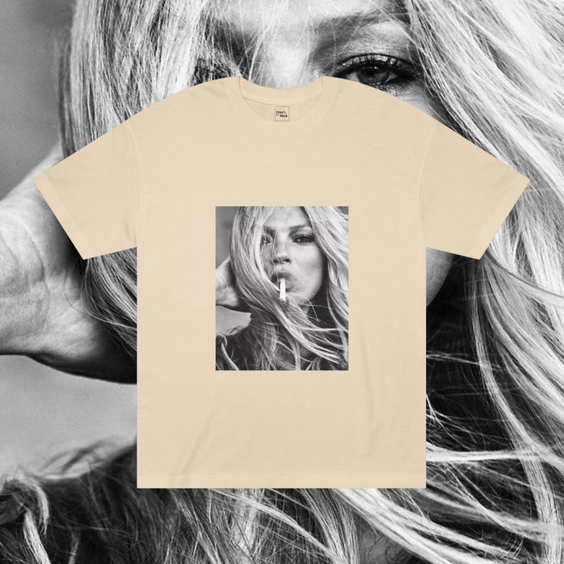 May include: A beige t-shirt with a black and white photo of a woman with long hair smoking a cigarette.