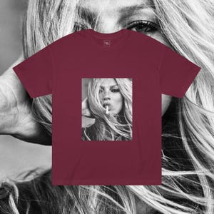 May include: A maroon t-shirt with a black and white photo of a woman with long hair smoking a cigarette.