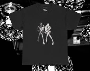 May include: Black and white photograph of two women wearing dresses and posing in front of a disco ball. The photo is printed on a black t-shirt.