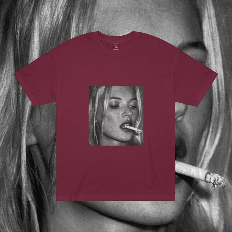 Puede incluir: Una camiseta color burdeos con una foto en blanco y negro de una mujer fumando un cigarrillo. La foto est&aacute; centrada en la camiseta.